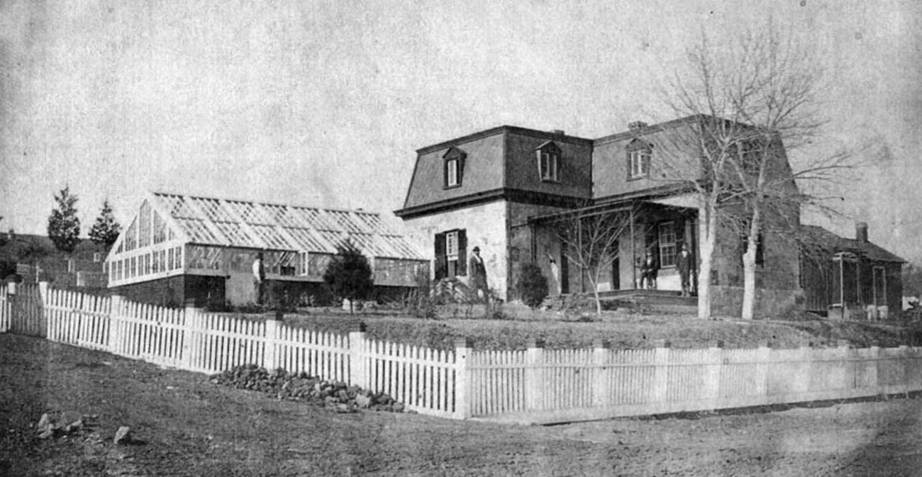 FRSP Lodge, Greenhouse, Toolhouse c. 1873 A pickett fence surrrounds a yard, greenhouse, and two story lodge with mansard roof