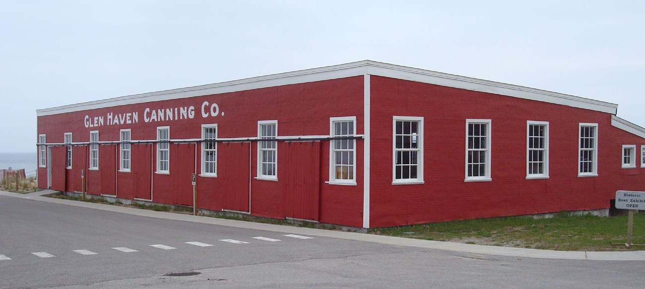 Single story cannery building is lined with windows and doors