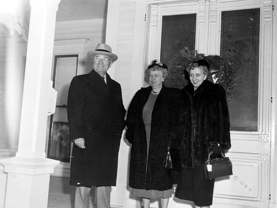 Harry S. Truman, Bess Truman, and Margaret Truman at in winter coats and hats on the porch of a house