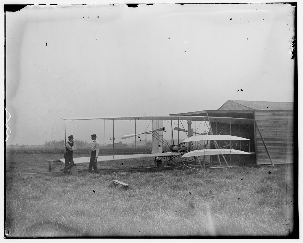 Wilbur and Orville Wright with their second powered machine beside a hanger; Huffman Prairie, Dayton, Ohio