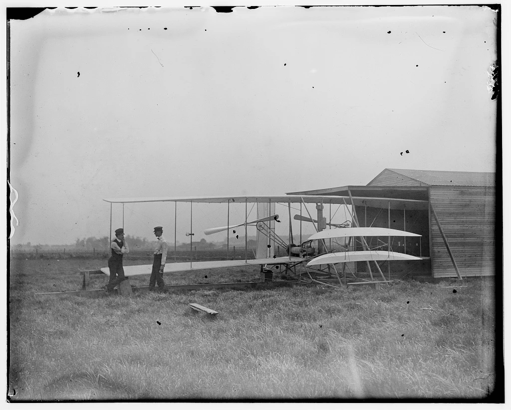 HUFFMAN FIELD IMAGE_LANDSCAPE PROFILE Wilbur and Orville Wright with their second powered machine beside a hanger; Huffman Prairie, Dayton, Ohio