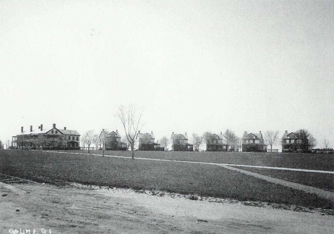 A uniform row of two-story houses lines the edge of a flat, open field