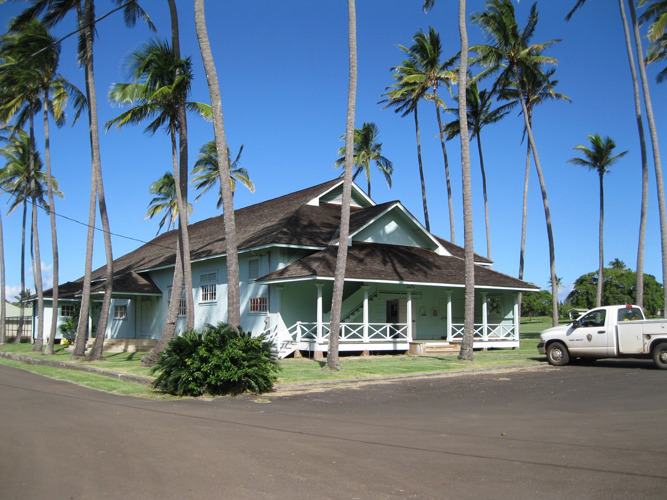 Paschoal Hall A rectangular community building with a porch, surrounded by palm trees