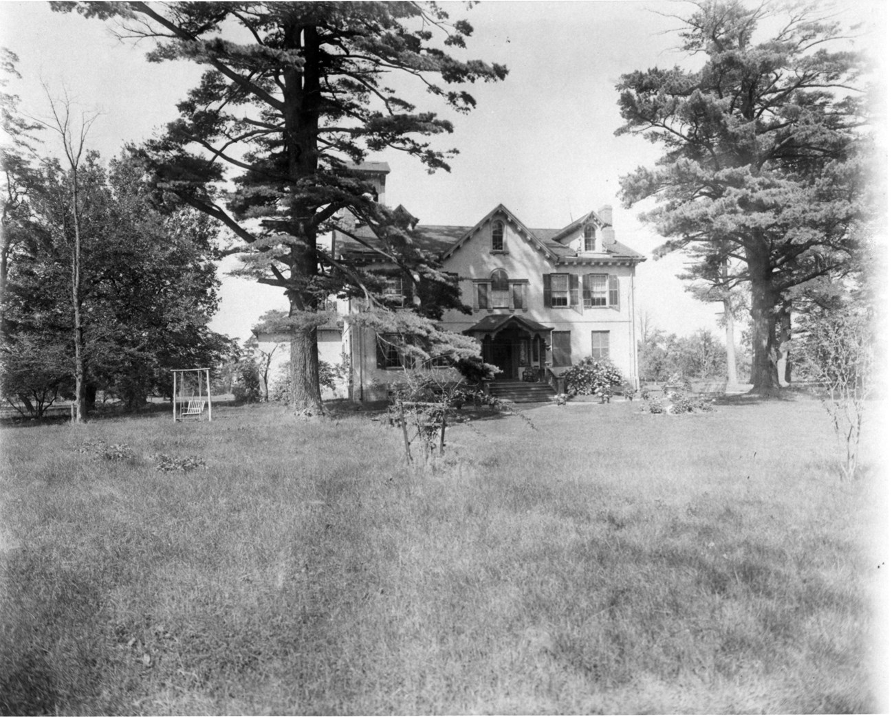Historic photo of the two-story Lindenwald mansion, framed by lawn and trees