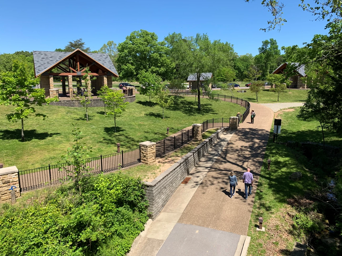 Treatment Recommendations A high-angle view shows a visitor area including pathways, fencing, trees scattered in turf, and rustic, pavilion-like structures