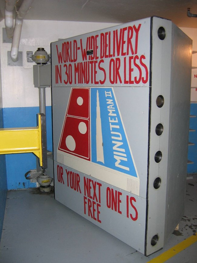 MIMI blast door Blast door of the Launch Control Center vestibule with a painted image similar to pizza company logo: "World-Wide Delivery in 30 minutes or less or your next one is free"
