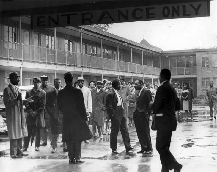 A crowd, including Martin Luther King, Jr., in the rainy courtyard of the Gaston Motel.