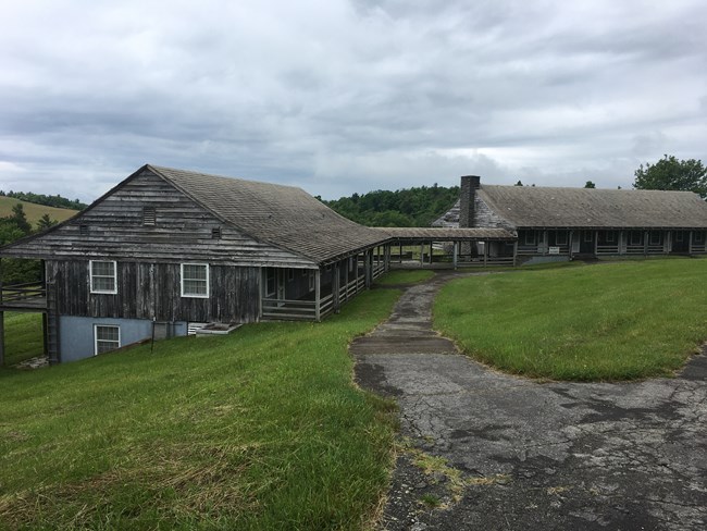 A walkway through turf approaches Bluffs Lodge, low buildings with wood siding built into a slope.