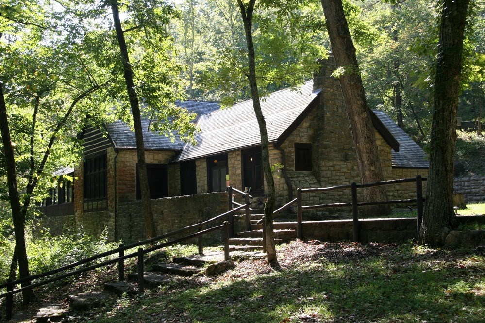 Stone stairs with wooden railing lead to a stone dining lodge with large windows