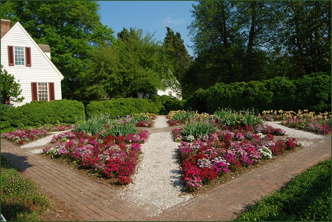 Brick and crushed stone pathways neatly divide low flower beds.