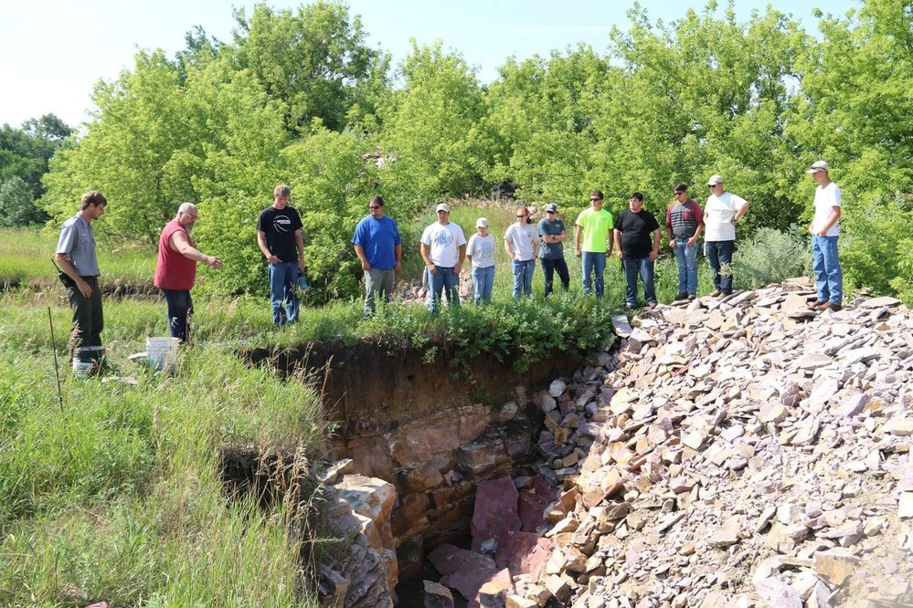 Quarrier and carver Travis Erickson at a quarry with a group of youth as he explains the process.