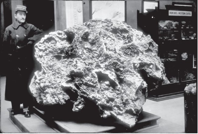 A man stands beside an irregularly shaped six-ton zinc nugget in an 1893 photo