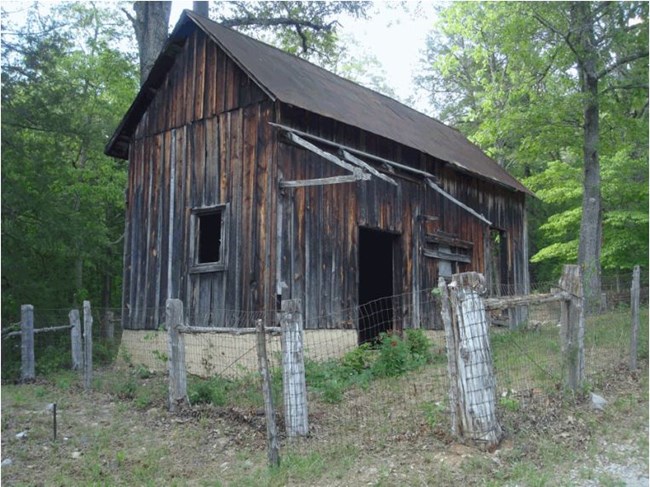 A blacksmith shop has wooden siding and a sloped metal roof