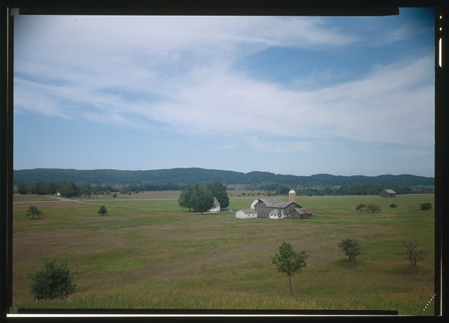 SLBE_Port-Oneida-Klett-LOC572197cv A cluster of farm buildings, including a house in a group of trees, stands in the middle of an open field.