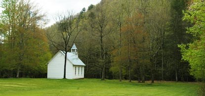 White chapel surrounded by green forest and grass in Great Smoky Mountains National Park.