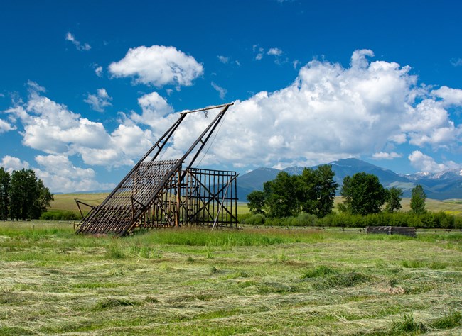 a large frame structure against the backdrop of cultivated hay fields and Mount Powell.