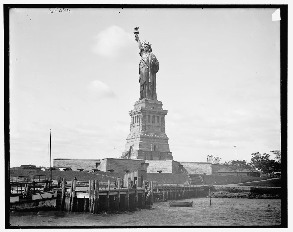 Wooden docks and an earthen berm with cannons at the base of the pedestal of the Statue of Liberty