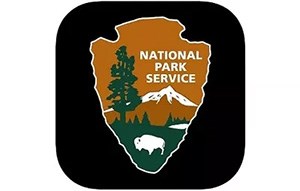 The US NPS Arrowhead with a bison, tree, and mountain.