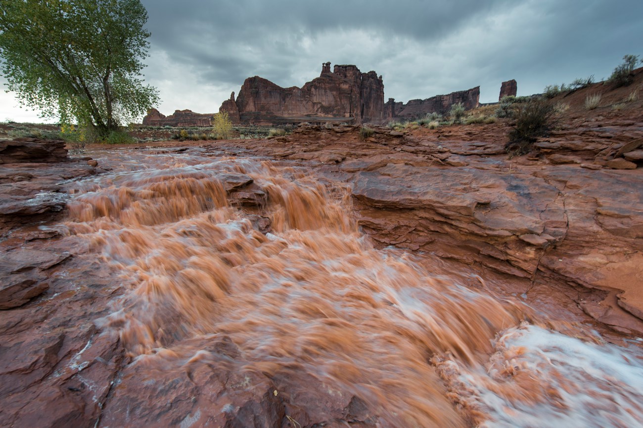 flash flooding in the desert showing muddy runoff flowing over bedrock