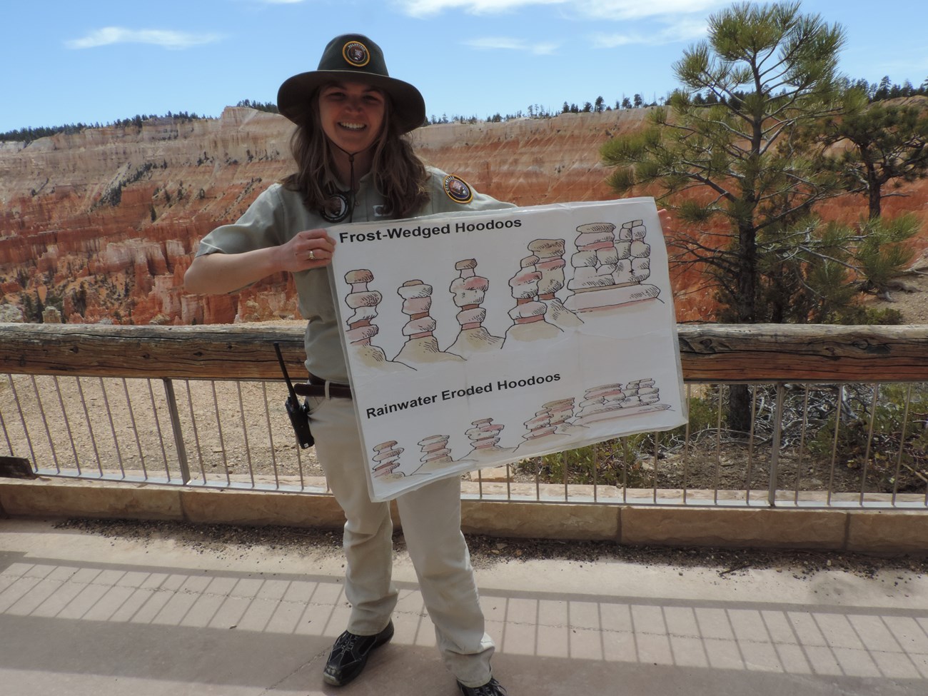 BRCA Joy Kiefer with a poster that she used for her Geology Talk nps by geoscientists-in-the-parks person standing at canyon rim holding poster with drawings of rock formations