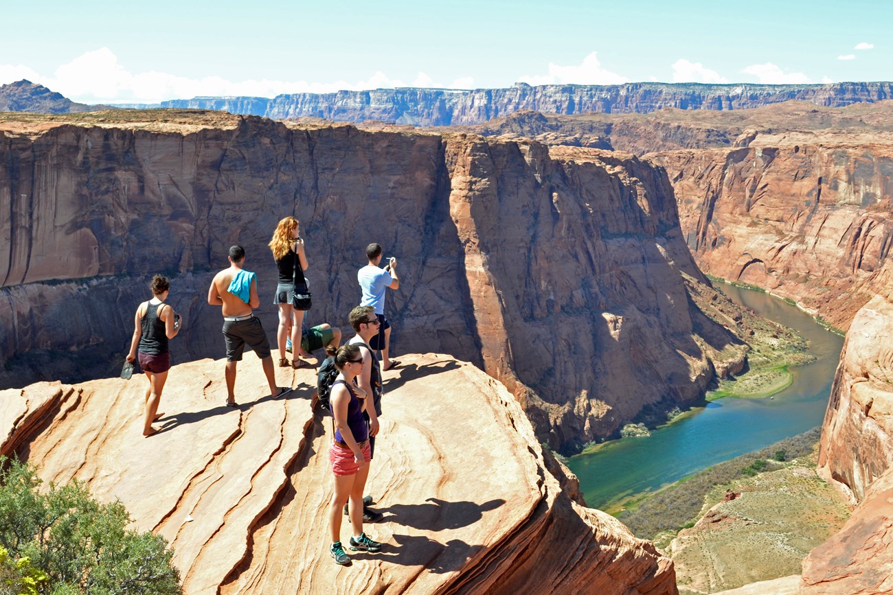 people at the top of a cliff looking into river canyon below