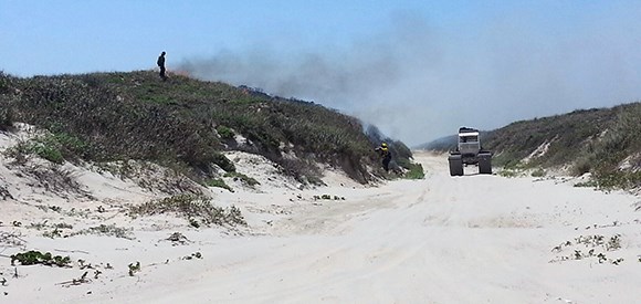 Firefighter conducts burnout operations with the support of a USFWS Marsh Master 28 Mile fire.