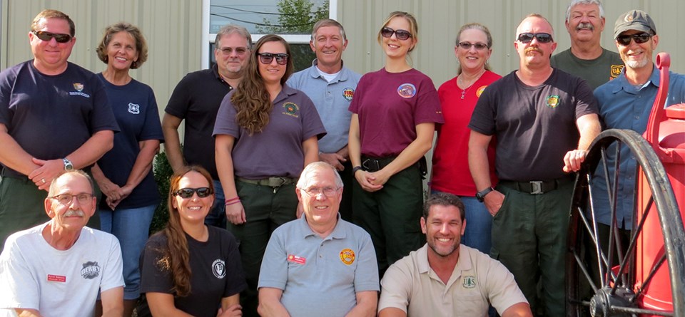 Men and women wearing a variety of agency shirts pose in a group.