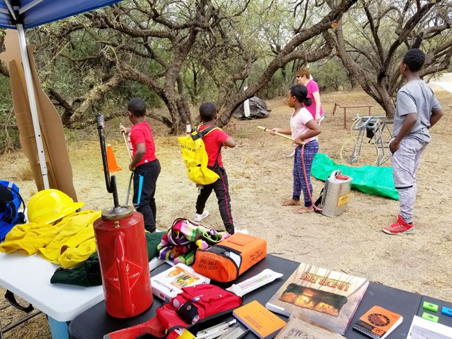 Students practice with handheld water pumps while learning about fire in Tumacacori National Historical Park. Students practice with handheld water pumps while learning about fire.