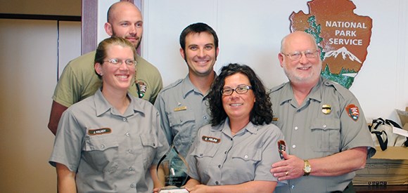 Members of the Natchez Trace fire effects modules crew accept the award for Achievement in Implementing Adaptive Management. A group of National Park Service employees holds an award.
