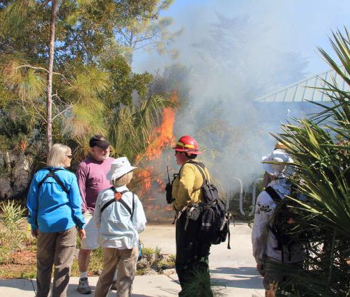 A group listens to a firefighter near the prescribed fire.