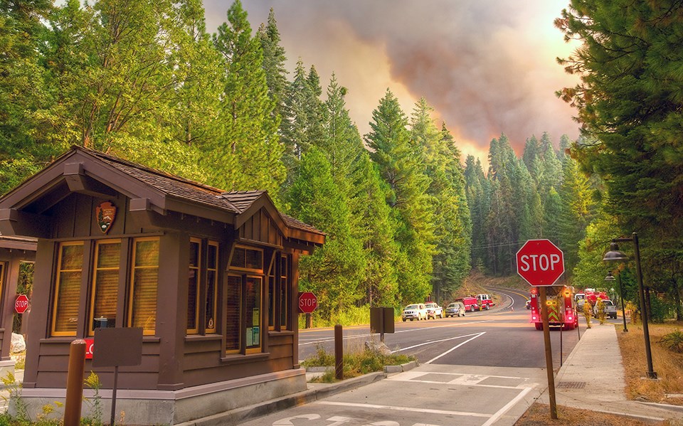 Yosemite park entrance station with a large plume of smoke in the distance.