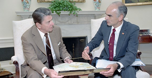 lt= President Reagan holds a map of Yellowstone while looking at Secretary Hodel to his right