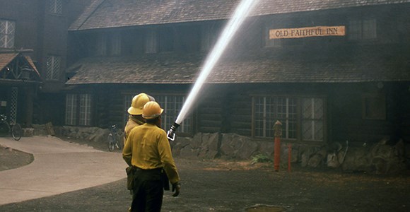 Two firefighters use a hose to spray foam on the Old Faithul Inn.
