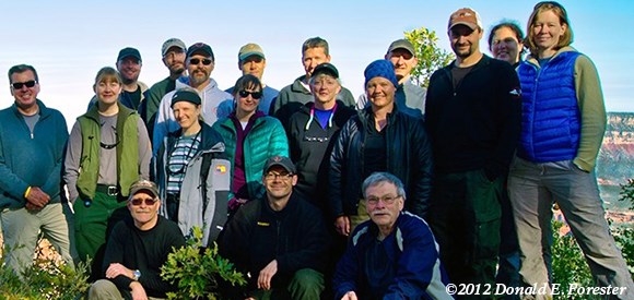 lt= A group is gathered at a viewpoint with the vista of the Grand Canyon behind.