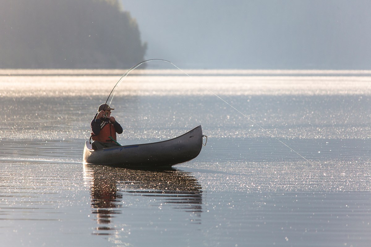 Fisherman in canoe on lake.