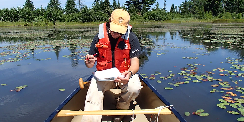 Recording data from the multi-probe. An NPS employee sits in a boat, he is writing on paper