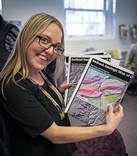 Georgia standing and holding colorful geologic maps