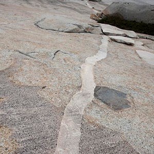 Photo of a light colored vein of rock with in a granite dome surface.