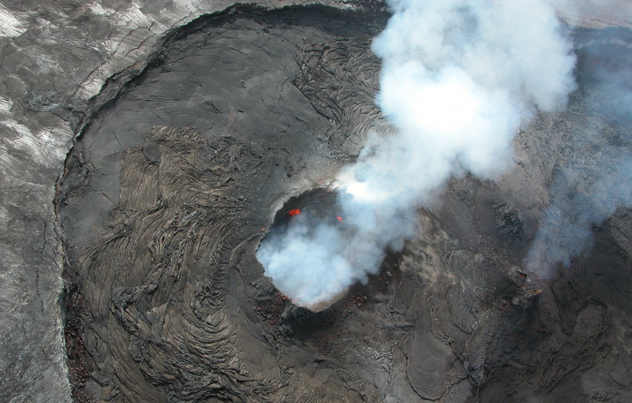 volcanic vent viewed from above. steam and molten lava visible.