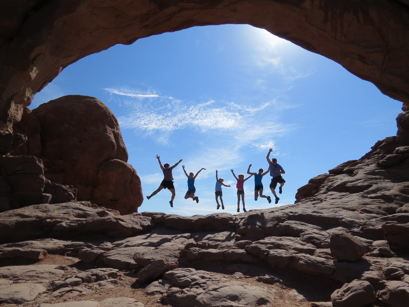 family jumping under rock arch