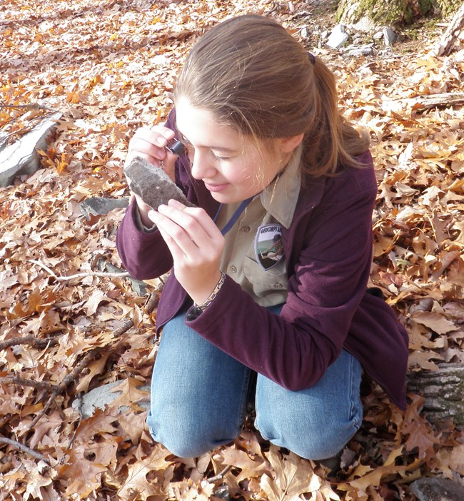 person with hand lens examining a rock