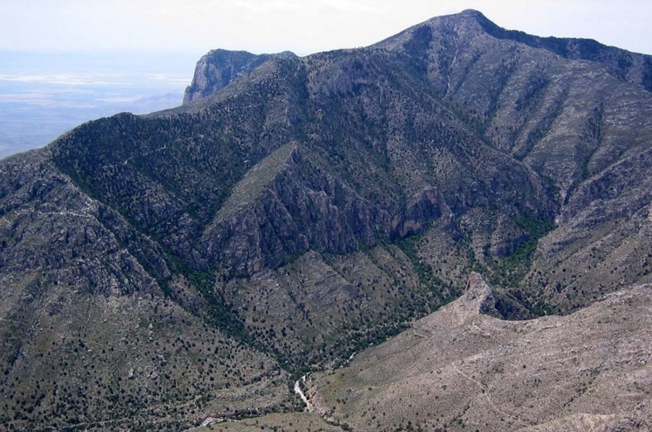 Photo of a mountain with cliffs and sparce vegetation.