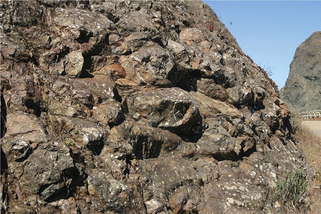 rounded basalt forms within rock face of a road cut
