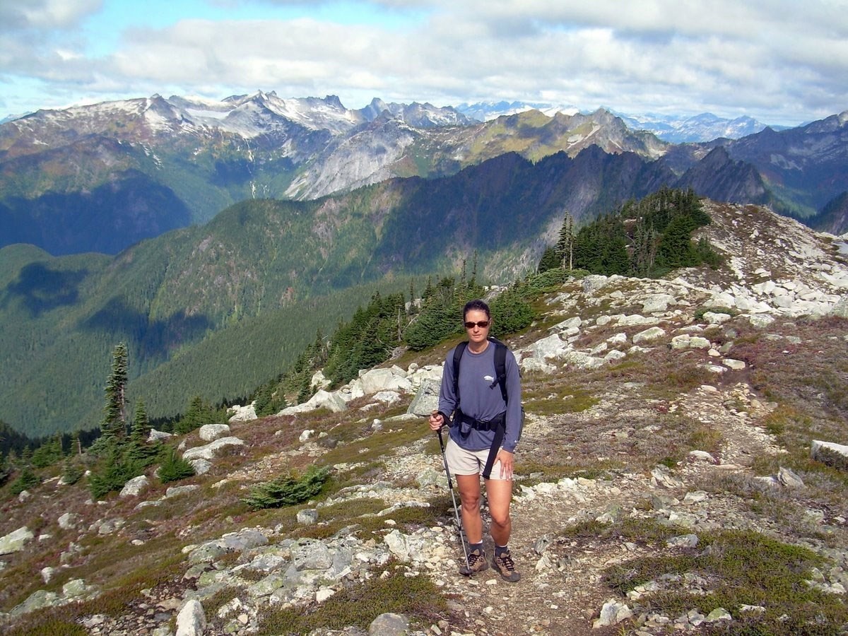 A hiker on a rocky trail with sharp peaks in the distance
