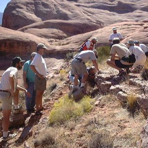 group of people examine rock outcrop