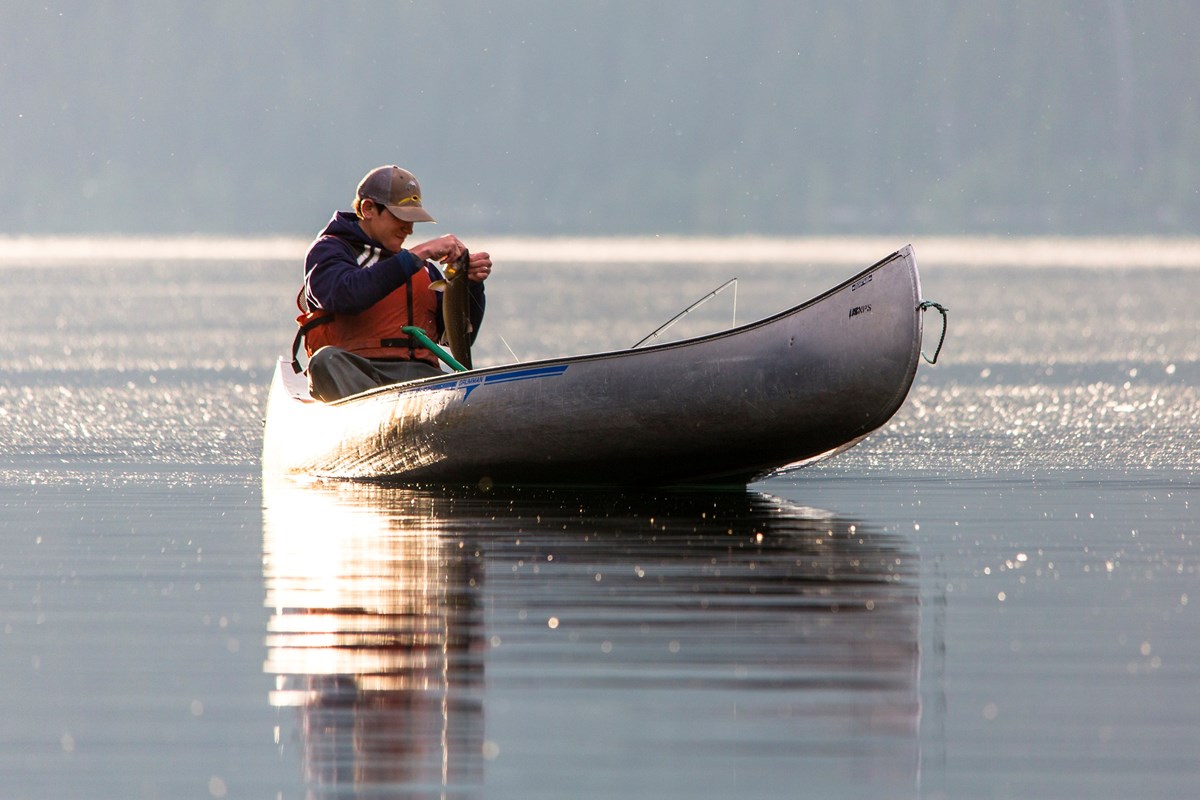 Fisherman unhooking fish from line at Quartz Lake