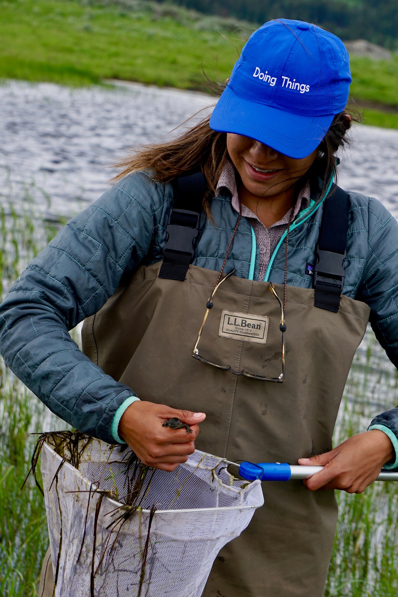 Young woman wearing blue hat holding fishing net.