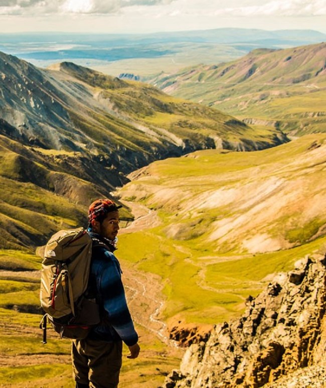 Hiker with pack standing at lookout over mountains