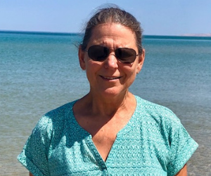 woman poses for a picture with body of water in the background