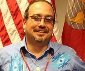 Learn more about panelist, Ty Smith. man poses with American flag in background